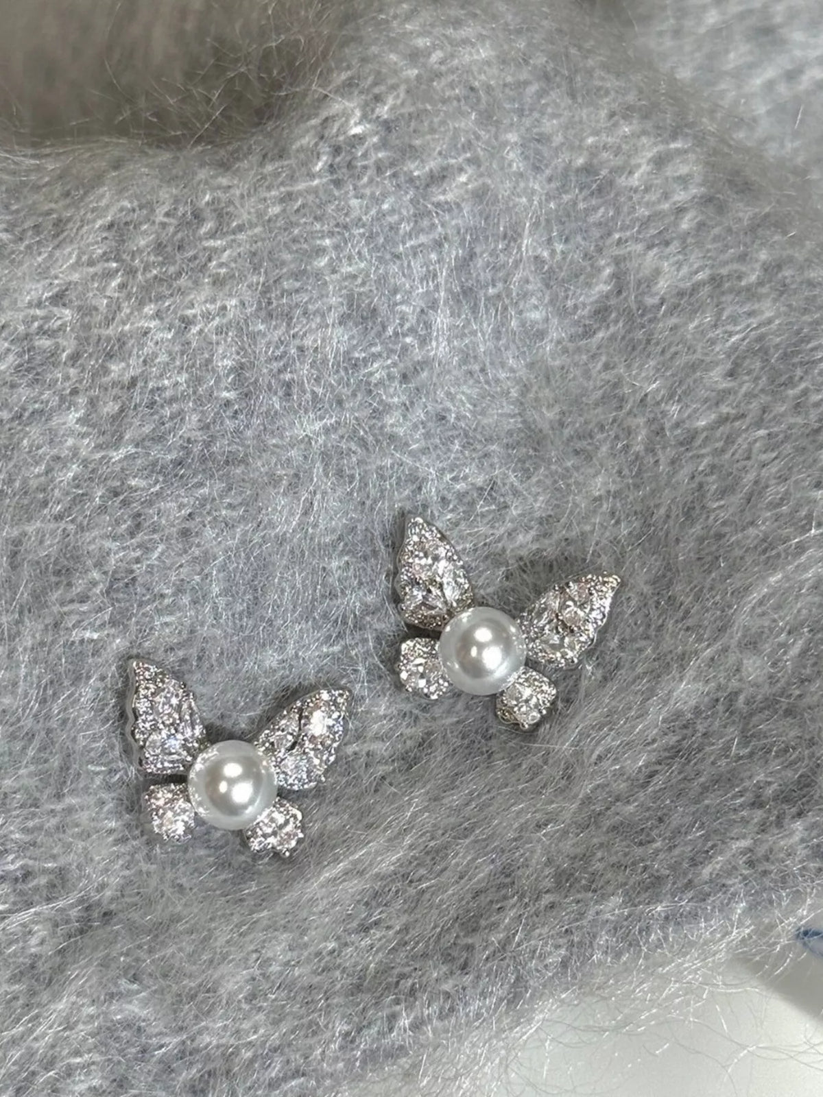 Elegant butterfly pearl stud earrings featuring white pearls and gold-tone accents, perfect for stylish fashion accessories.