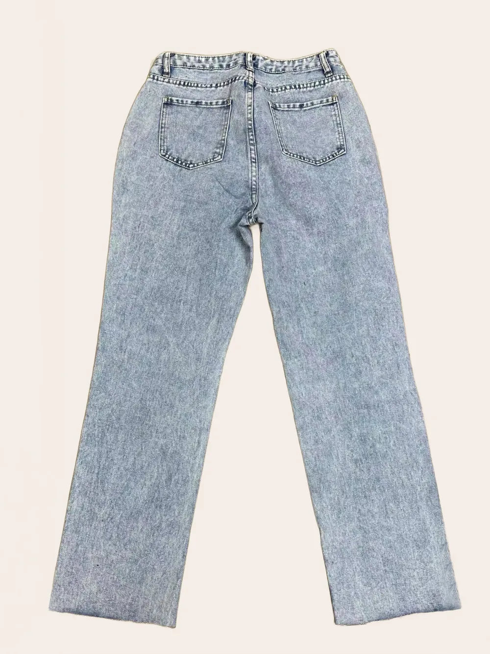 Distressed straight leg denim jeans with pockets by Trendsi, showing a close-up of the ripped and faded details on the fabric.
