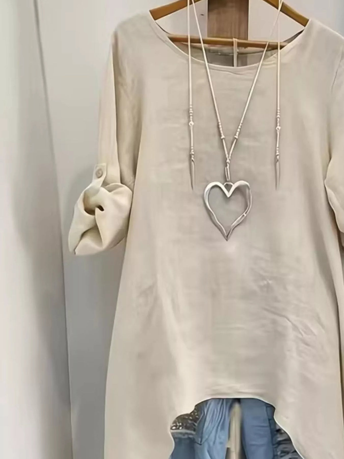High-low hem blouse with roll-up sleeves by Trendsi, featuring a stylish and flowy design perfect for casual or dressy wear.