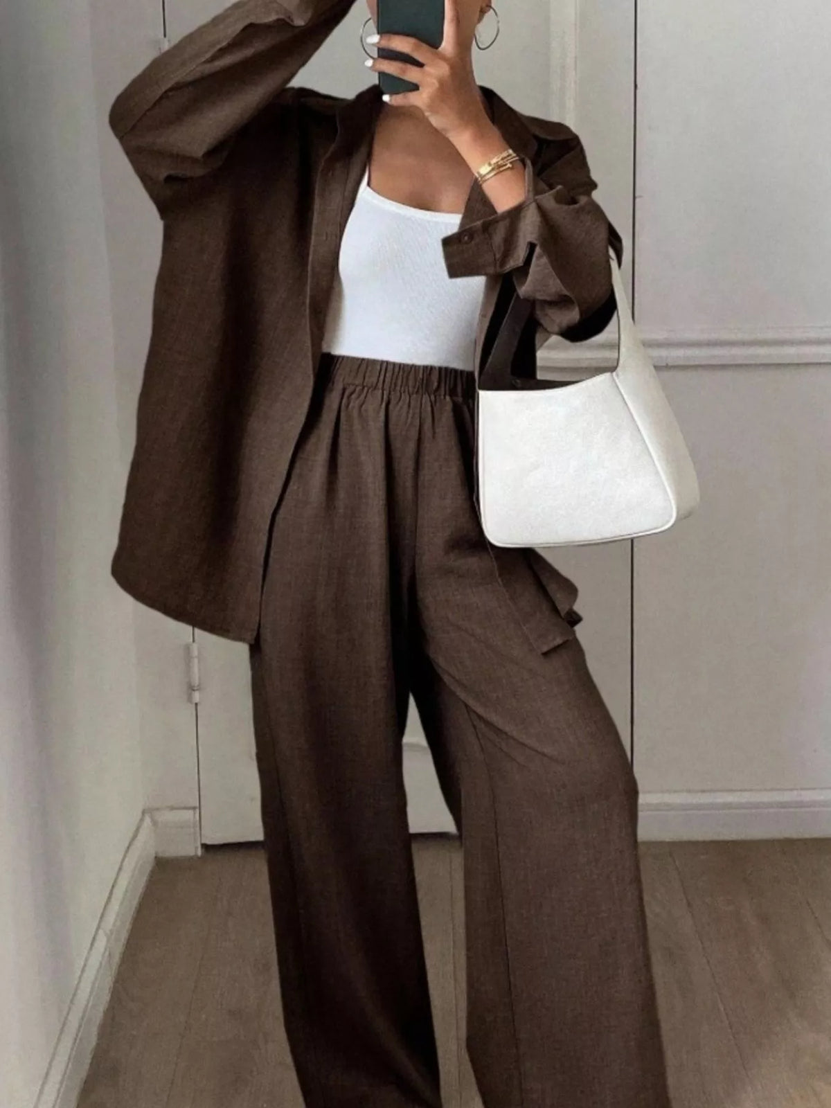 Trendsi long sleeve button-up shirt and wide-leg pants set shown on a model, featuring a stylish, coordinated outfit.