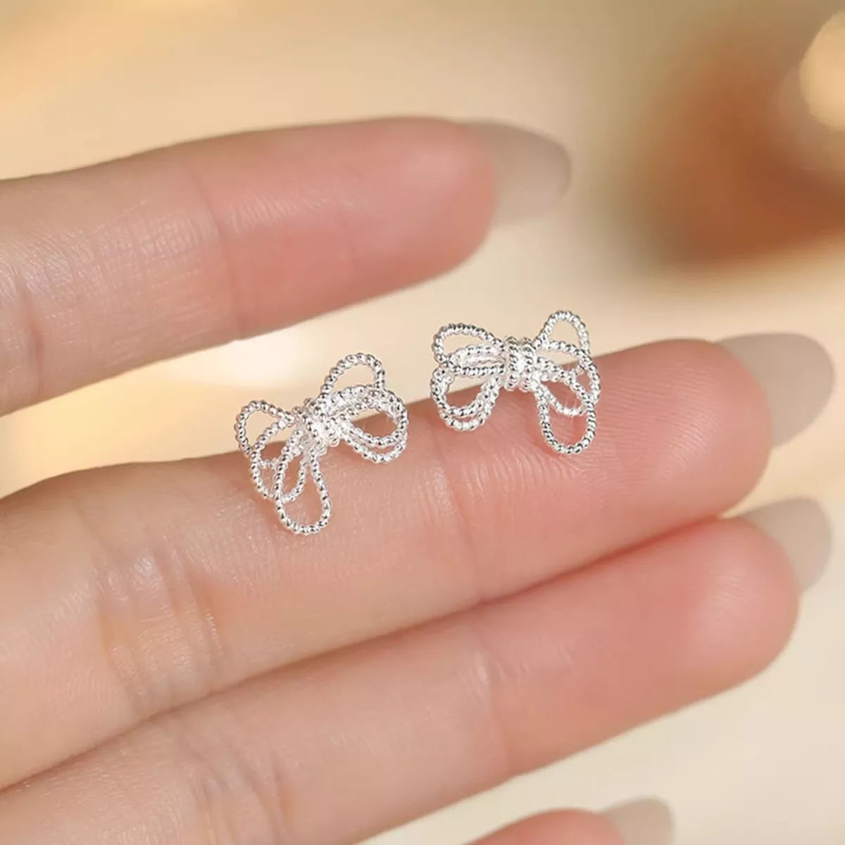Sterling silver bow knot stud earrings from Plush Fashion Hub, featuring elegant and simple jewelry design with shiny silver finish.