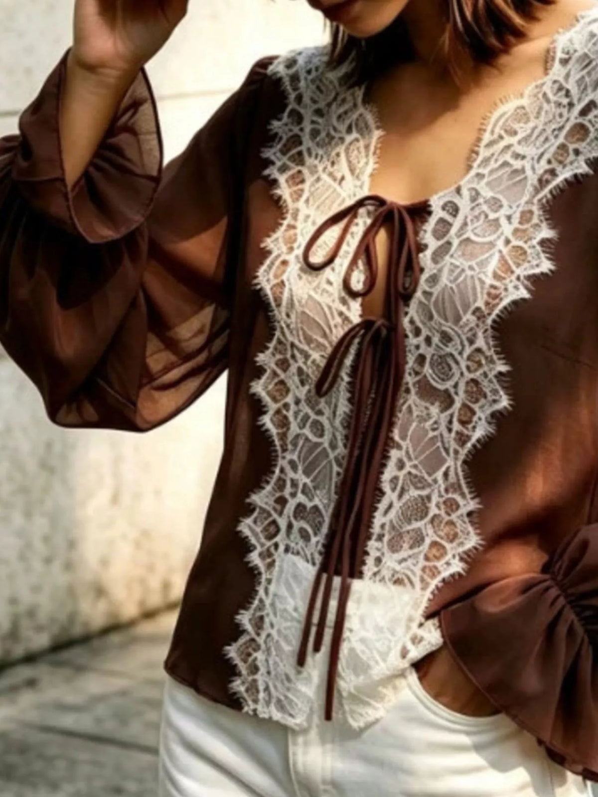 Sheer lace-trimmed front tie blouse for women by Trendsi, featuring delicate lace details and a stylish, feminine fit.