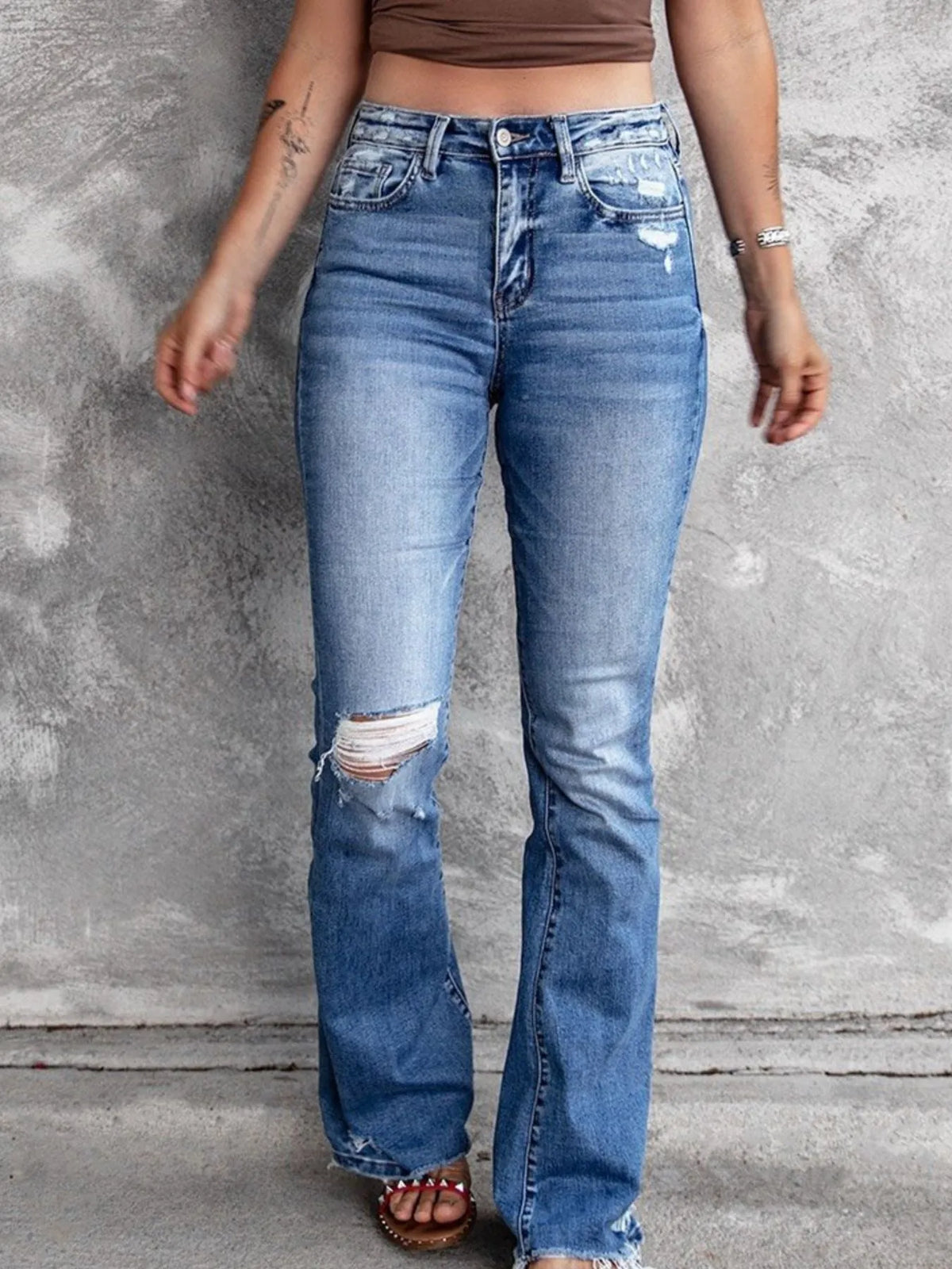 Distressed flare denim jeans by Plush Fashion Hub featuring ripped details and a high-waisted fit on model.