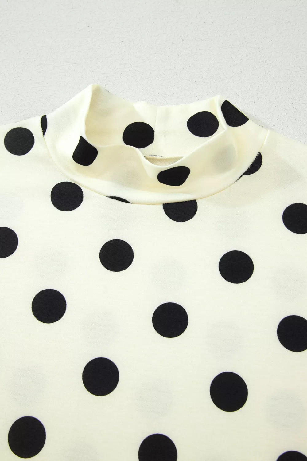 Polka dot print high neck dolman top from Trendsi, featuring a relaxed fit and long sleeves, perfect for casual or stylish outfits.