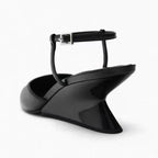 Elegant black patent leather wedge sandals with a sleek architectural heel and an adjustable ankle strap.