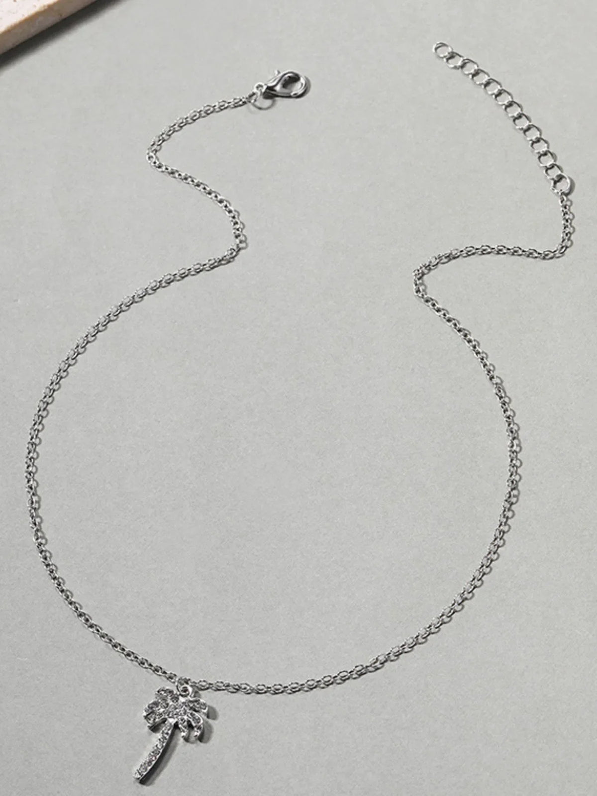 Zircon Palm Tree Pendant Necklace featuring sparkling zircon stones on a silver chain, designed by Plush Fashion Hub.