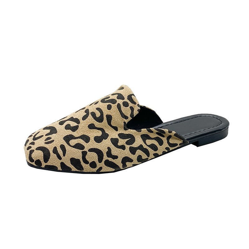 Tan suede mules with black leopard print, pointed toe, and a flat black sole. Slip-on style shoe.