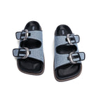 Light blue denim sandals with black trim, double wide straps, large silver buckles, and black molded footbeds.