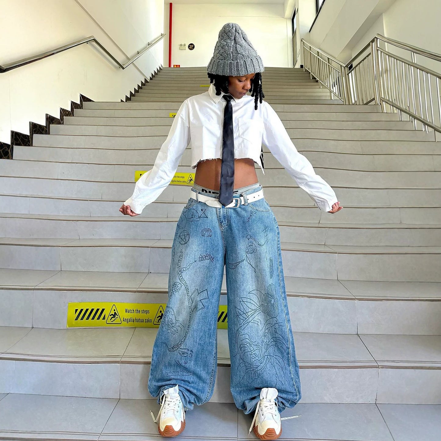 Eprolo graffiti print washed denim jeans showing distressed details and graffiti artwork on light blue denim fabric