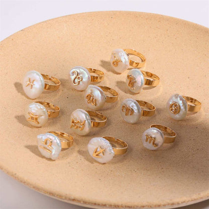 Gold Cosmic Constellation Rings with Zodiac Symbols on a Beige Plate.