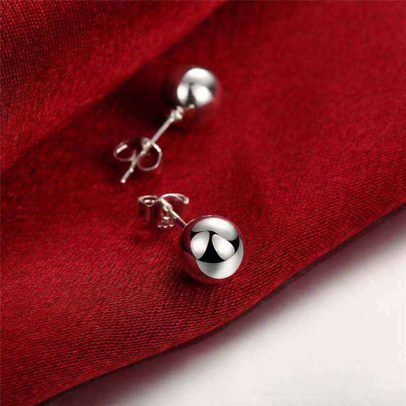 Creative bead stud earrings on red fabric with silver plating.