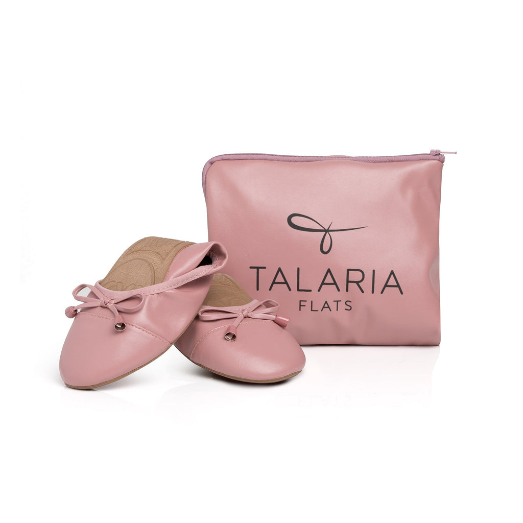 Talaria Flats in dusty rose color with folded design, displayed in front of a bag, showcasing stylish footwear for women.