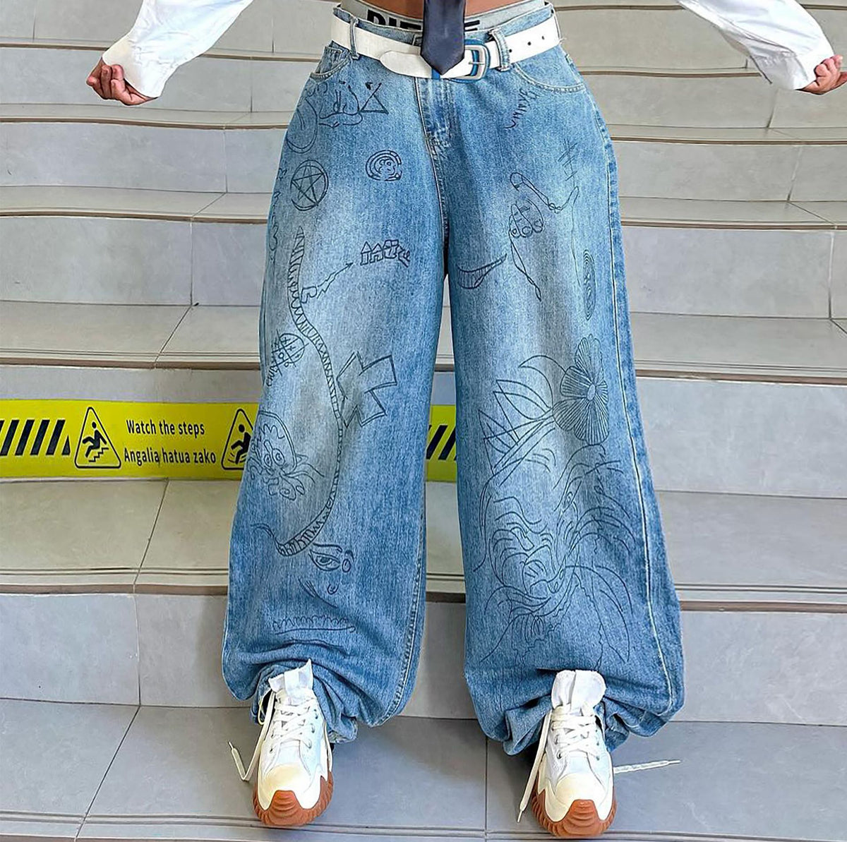 Stylish washed denim jeans with graffiti print by Plush Fashion Hub, featuring a casual fit and artistic streetwear design.