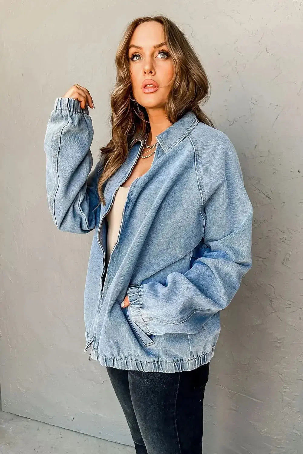 Zip-up denim jacket by Plush Fashion Hub featuring raglan sleeves and an elastic hem, shown on a model.