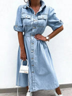 Plus size denim shirt dress by Trendsi featuring roll-up sleeves and front pockets, styled for casual wear.