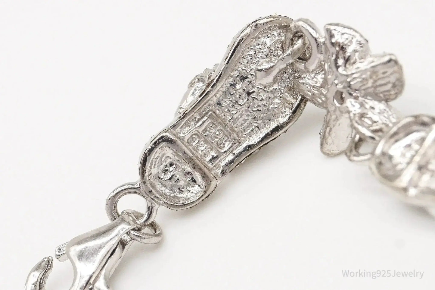 Sterling silver vintage bracelet with cubic zirconia sandals and flower charms, featuring intricate jewelry design.