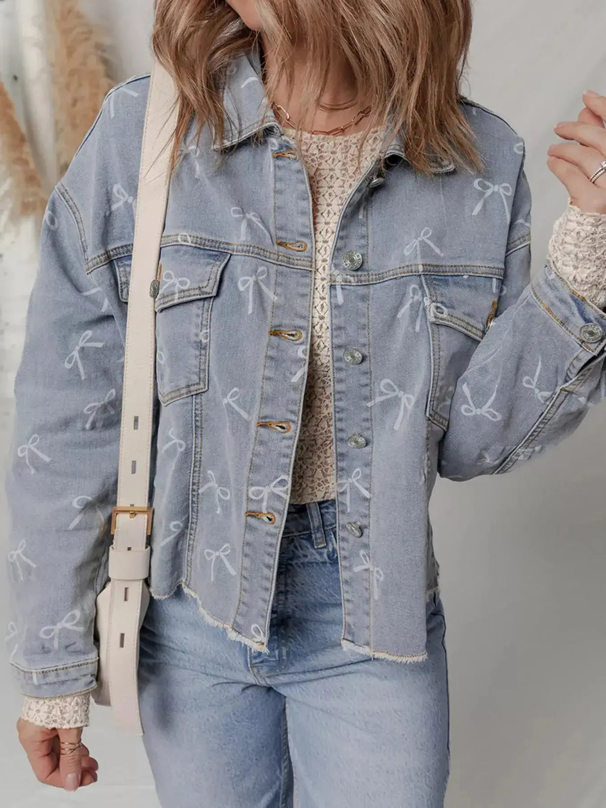 Women’s light wash raw hem denim jacket with bow knot print by Plush Fashion Hub, showcasing trendy casual outerwear.