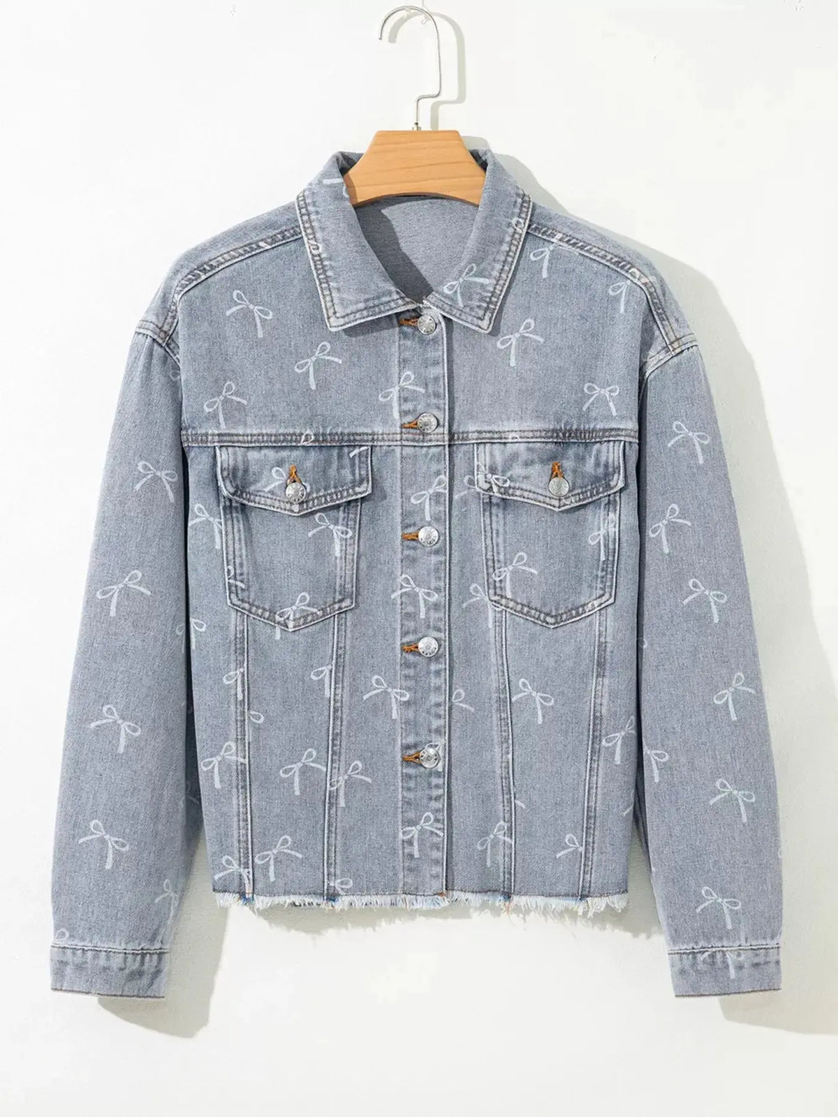 Women’s light wash denim jacket with bow knot print, raw hem, and trendy design by Plush Fashion Hub.