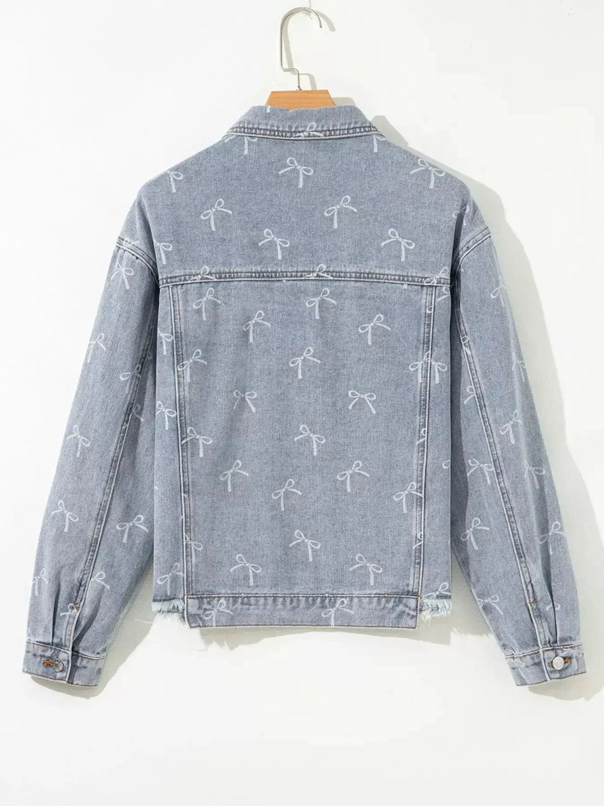Women’s light wash denim jacket with bow knot print and raw hem from Plush Fashion Hub, featuring a trendy, casual style.