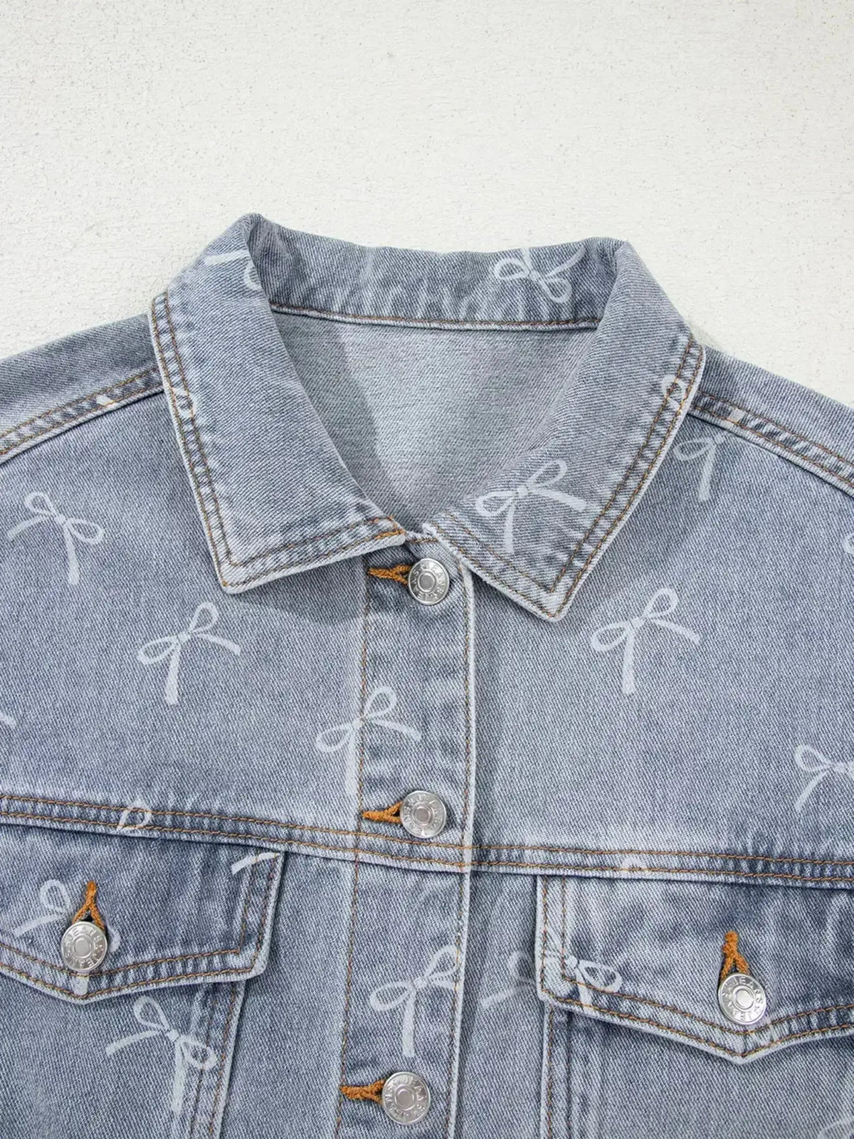Women’s light wash raw hem denim jacket with bow knot print by Plush Fashion Hub, featuring a trendy casual style.