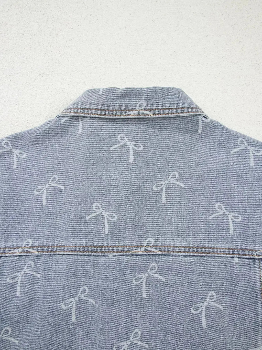Light wash denim jacket with bow knot print, raw hem, and classic fit, designed for women by Trendsi.