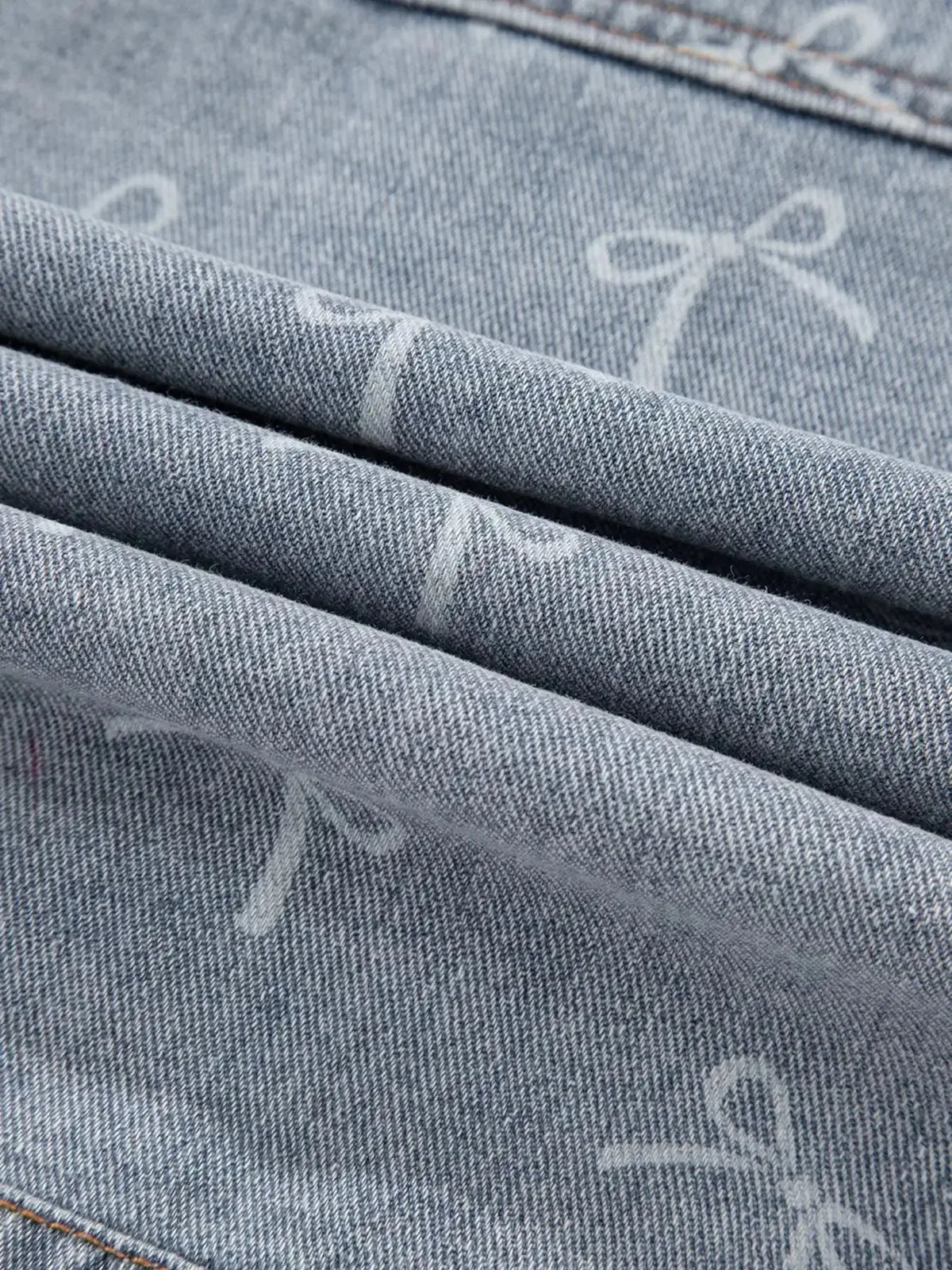 Women’s light wash denim jacket with bow knot print and raw hem, featuring a stylish design by Plush Fashion Hub.