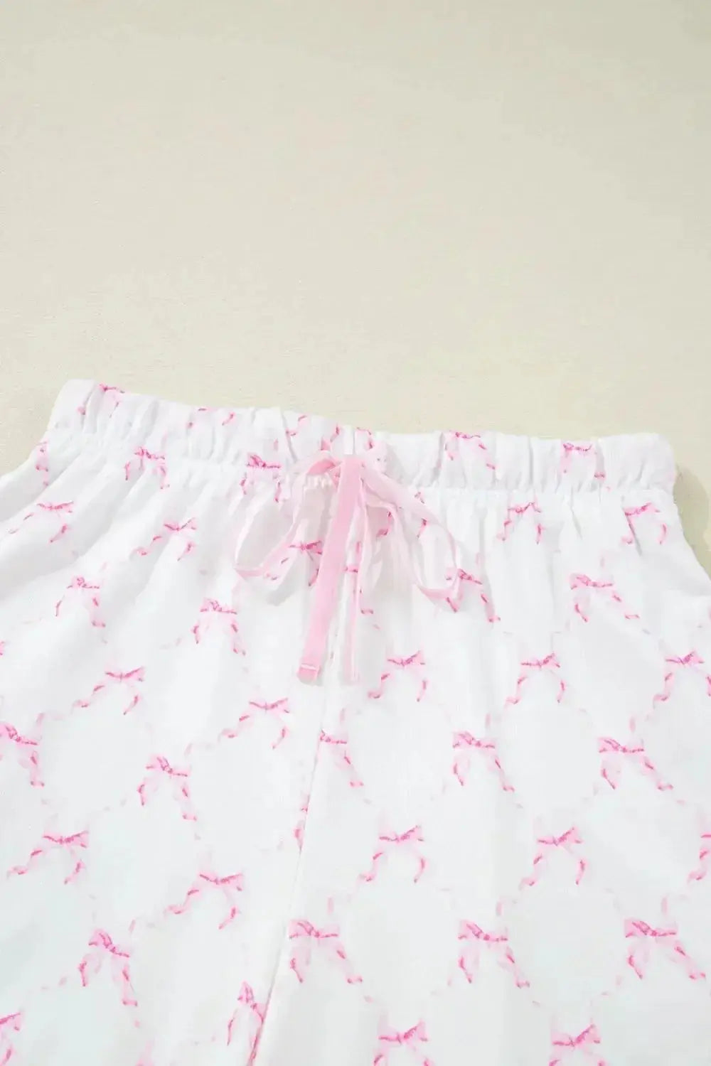 Women's bow print lounge set by Trendsi featuring soft pajamas with lettuce trim and matching shorts.