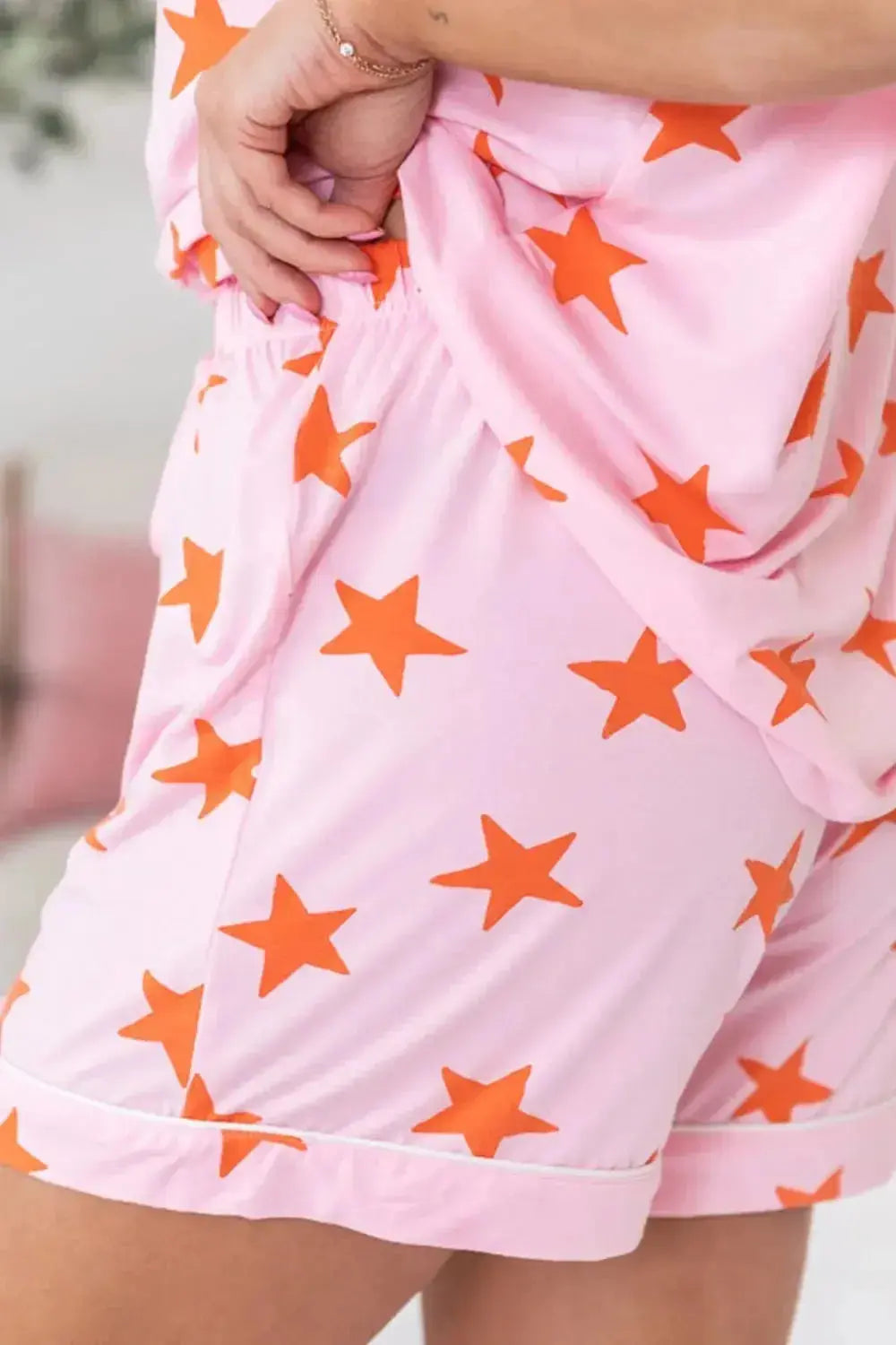 Women's star print short sleeve button-down pajama set by Trendsi, featuring a comfortable, stylish sleepwear design with button front.
