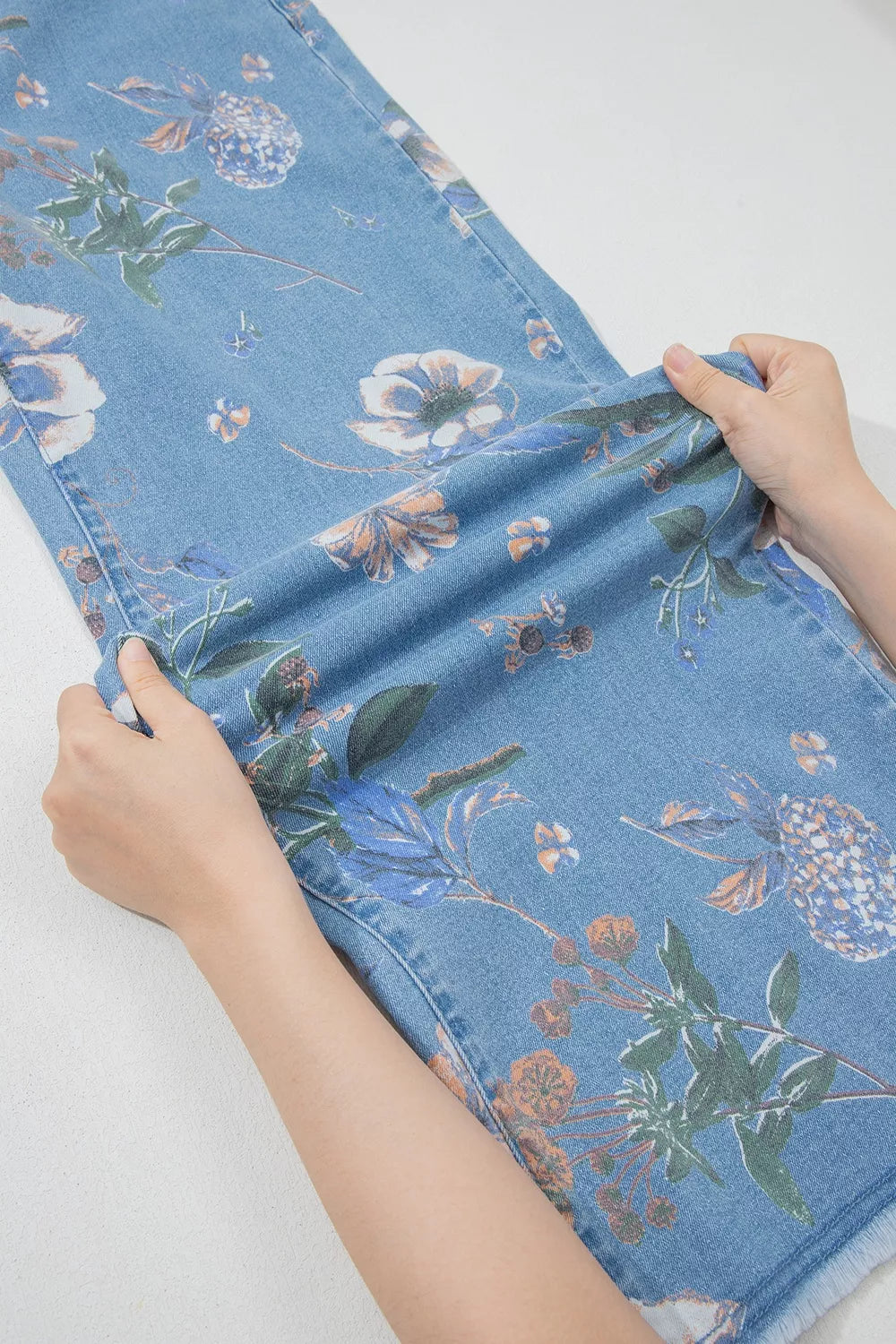 Floral print wide-leg jeans from Trendsi featuring a high waist and relaxed fit, with vibrant floral patterns and denim fabric.