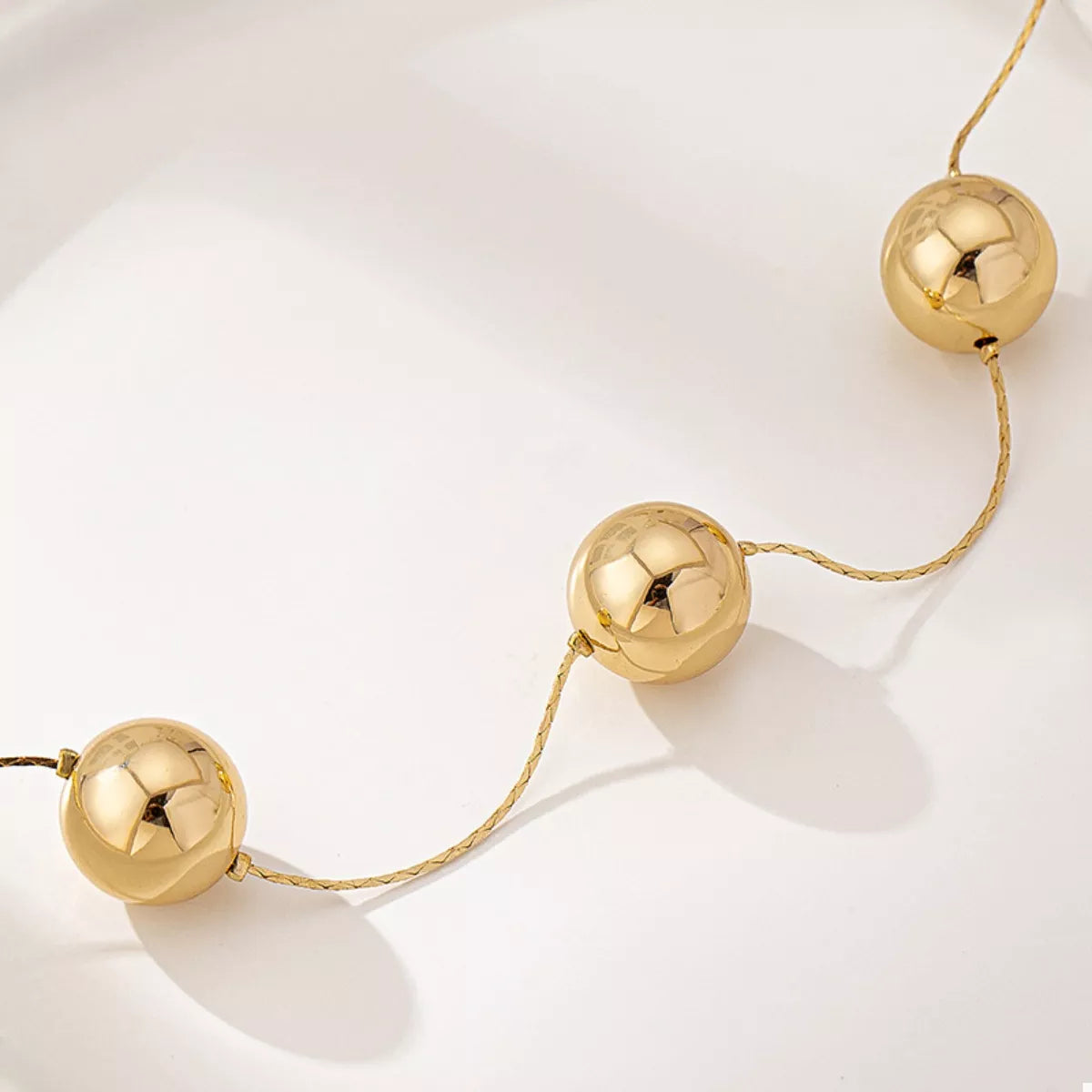 Golden Sphere statement necklace from Plush Fashion Hub featuring large shiny gold orbs on a sleek chain.