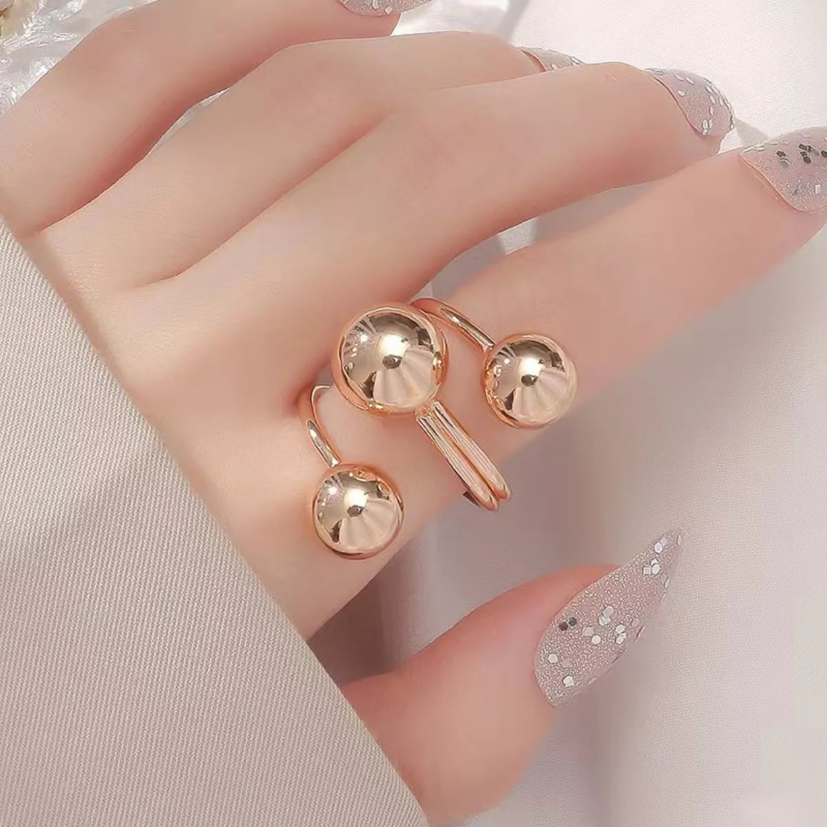 Multi-layered ball ring from Plush Fashion Hub featuring stacked metal bands and spherical accents on a white background.