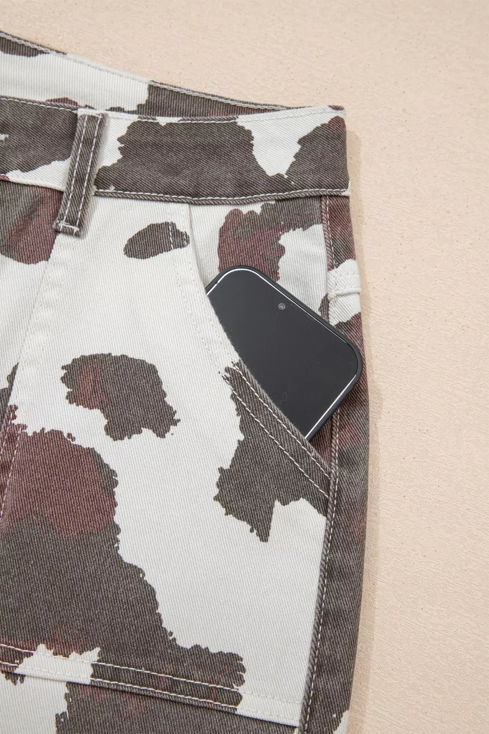 Cow spots printed multi-pocketed jeans from Plush Fashion Hub featuring black and white cow print design and multiple functional pockets.