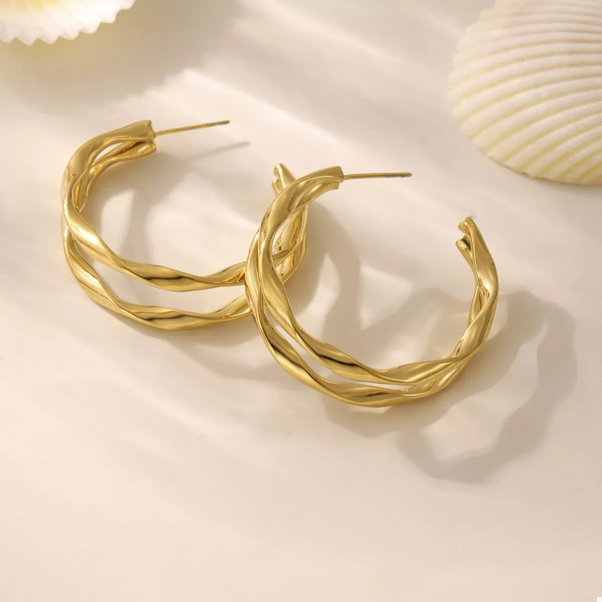 Gold-plated chunky twisted hoop earrings with a shiny finish, stylish and bold jewelry accessory.