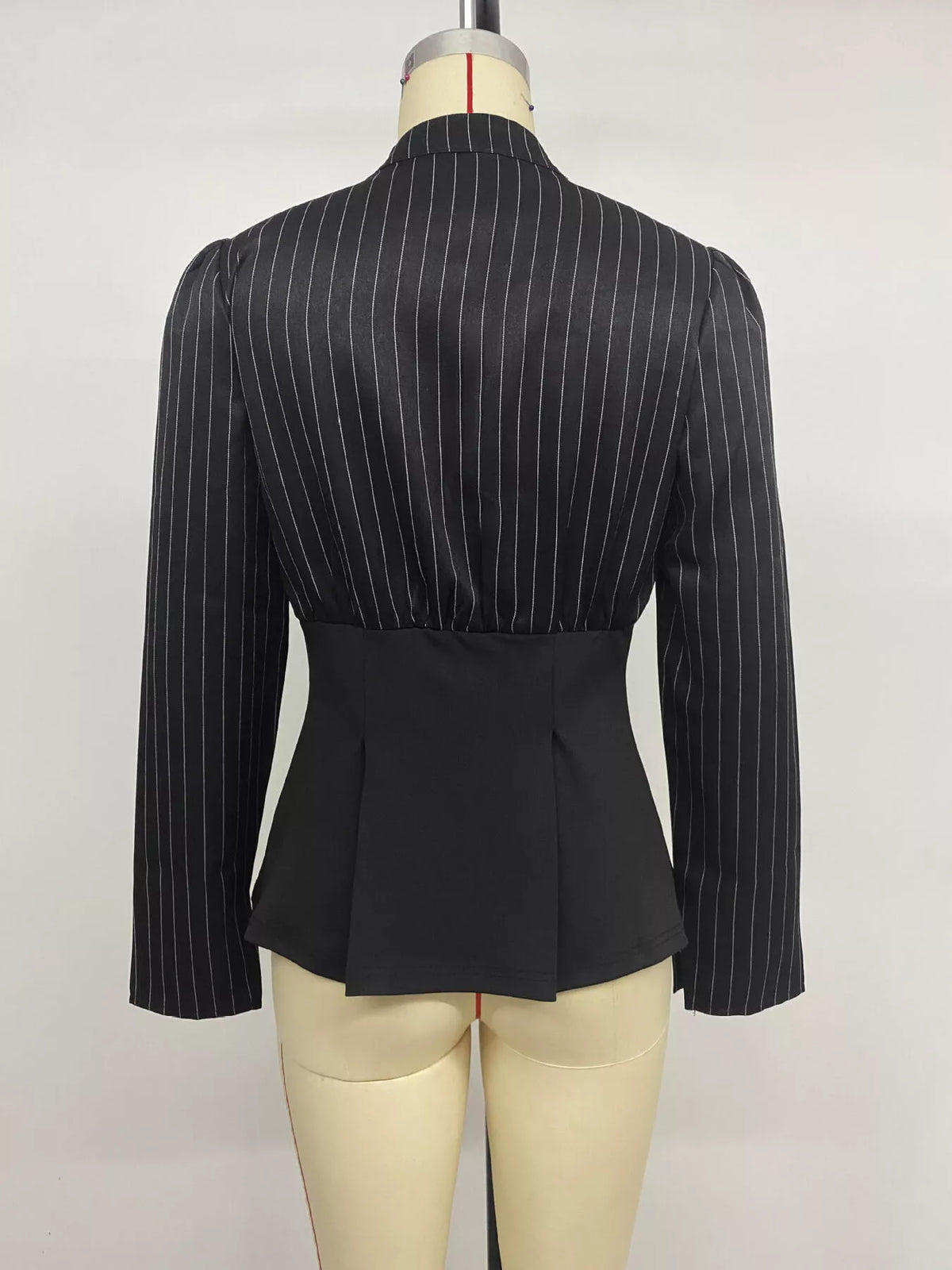 Striped long sleeve peplum blouse for women by Trendsi, featuring a fitted waist and stylish design with bold vertical stripes.