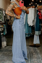 Women's distressed wide-leg denim overalls with casual relaxed fit, featuring a trendy, worn-in look and adjustable straps.