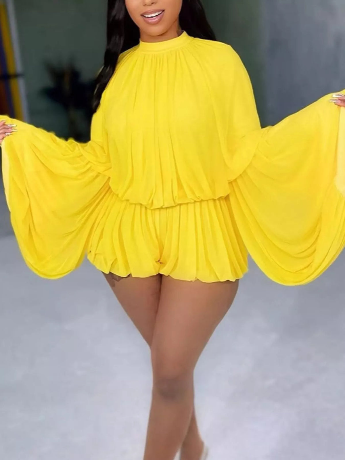 Elegant pleated bell sleeve romper by Trendsi featuring a stylish design and flowing fabric, shown on a model.