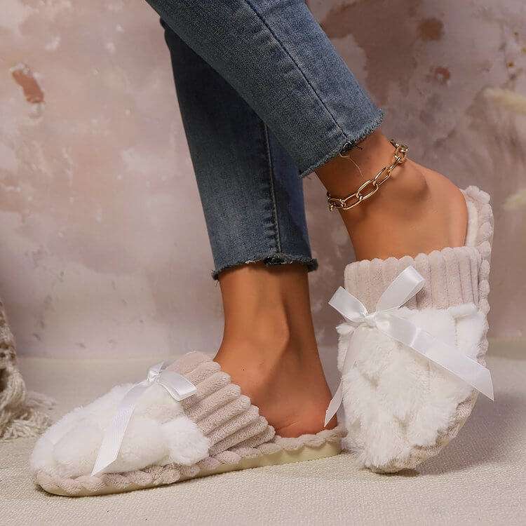 Bow Trim Contrast Slippers in neutral shades with a fluffy texture and bow accent, worn by a person in jeans.