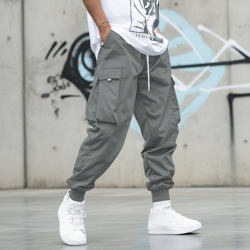 Men’s multi-pocket drawstring cargo pants from FitiqueFit streetwear collection, showing side view with multiple functional pockets.