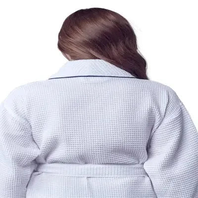 Back view of small white knee-length waffle robe for women with piping from Lotus Linen, showing the relaxed fit and textured fabric.