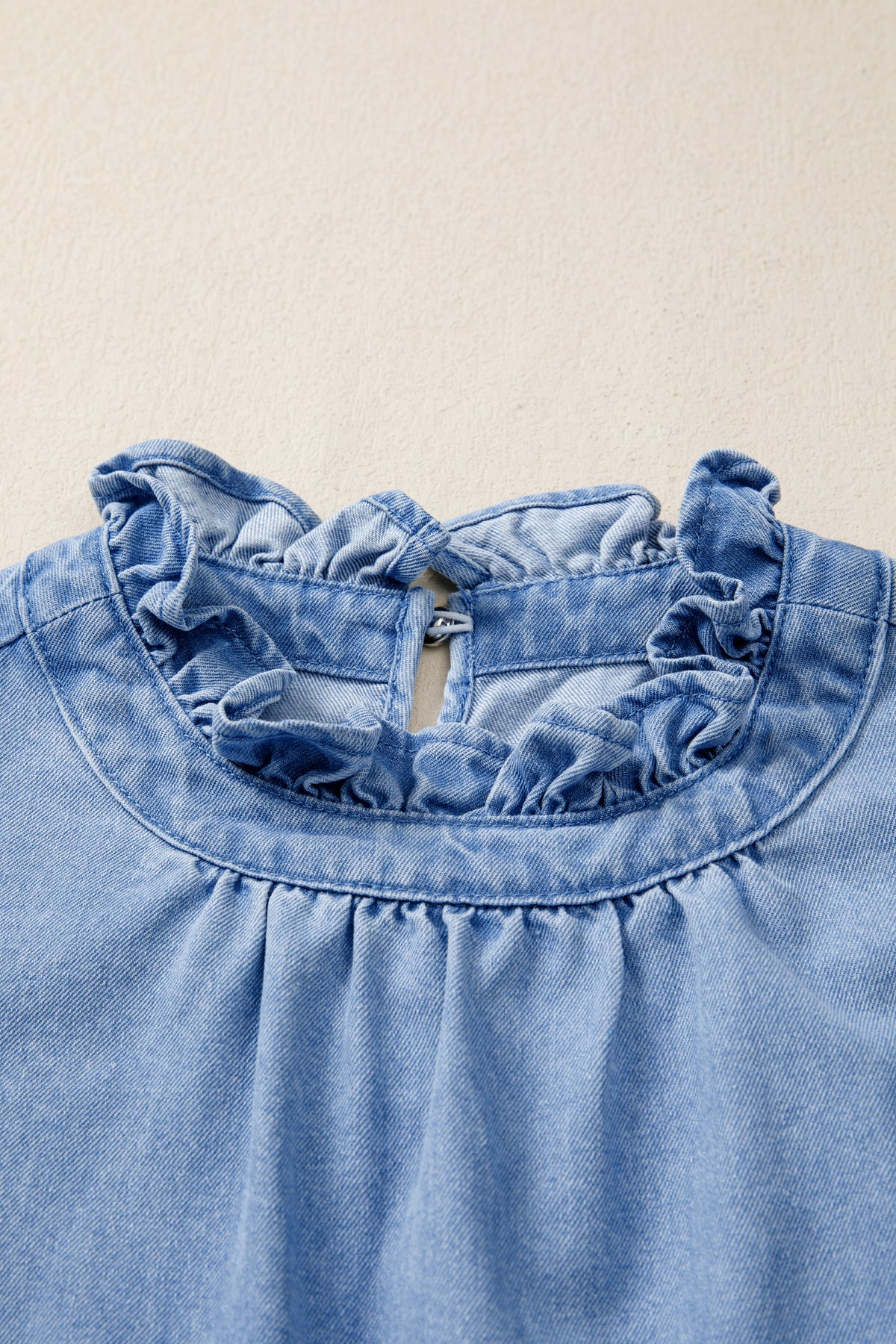 Women's distressed denim top with frilled collar and flutter sleeves, stylish and casual from Plush Fashion Hub.