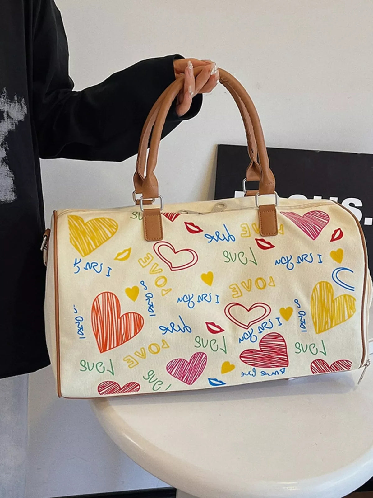 Printed duffel bag with adjustable strap from Plush Fashion Hub, showing a spacious bag with colorful printed design and sturdy handle.