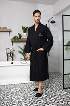Black Lotus Linen men's waffle spa bathrobe, lightweight and absorbent, shown hanging on a hook.