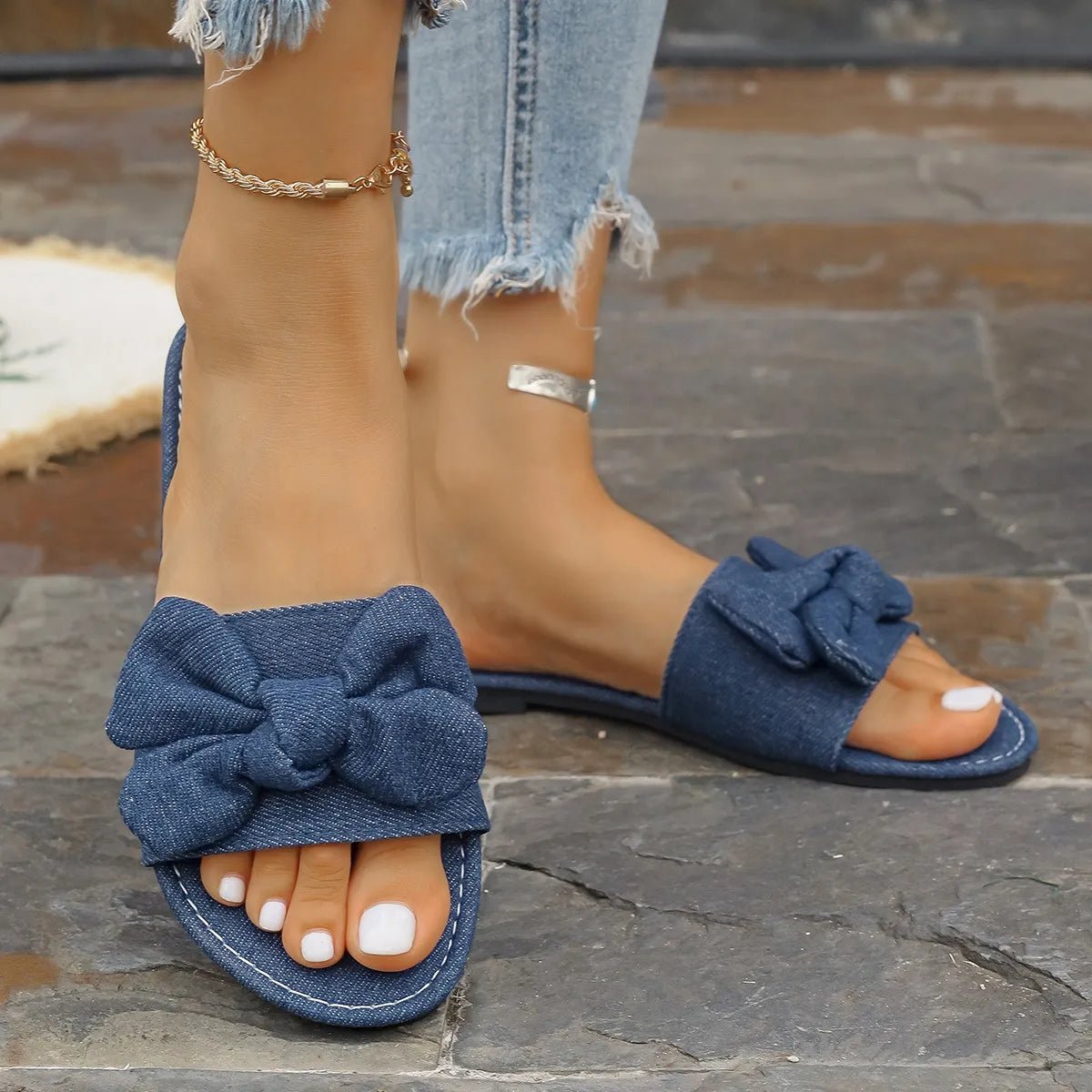 Women's denim flat sandals with bow tie detail and casual PU leather straps, offering comfortable style for everyday wear.