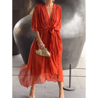 Batwing sleeve V-neck midi dress with tied irregular hem from Plush Fashion Hub, featuring flowy fabric and elegant silhouette.
