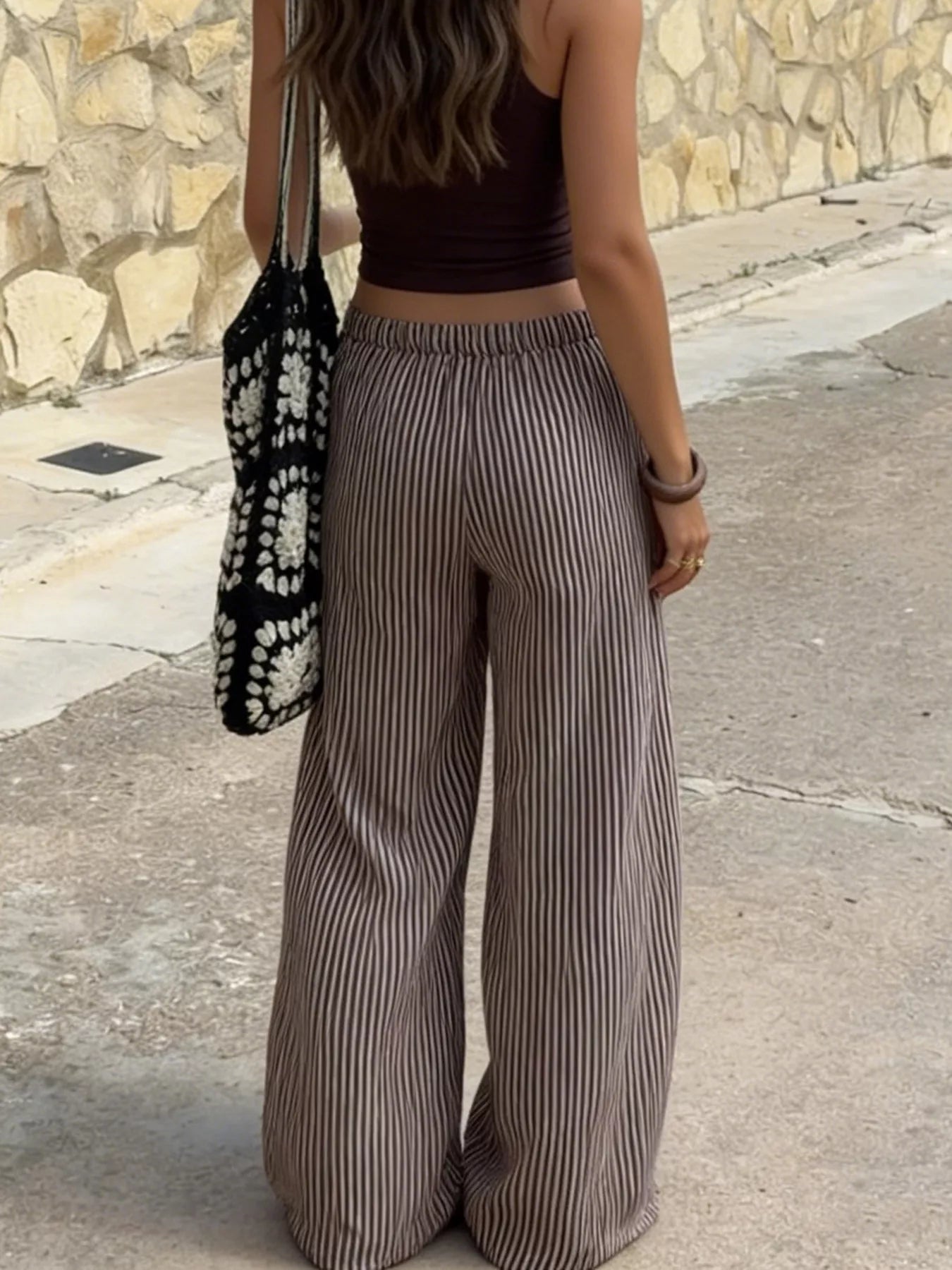 Tied striped wide-leg pants in neutral tones, featuring a relaxed fit and high waist, perfect for casual or stylish outfits.