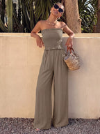 Smocked strapless wide-leg jumpsuit by Trendsi featuring a fitted bodice and flowing wide-leg pants, perfect for warm-weather wear.