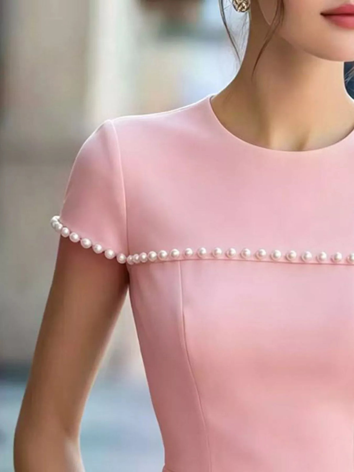 Pearl-embellished plush fashion hub peplum T-shirt with short sleeves and round neckline, featuring elegant pearl details.