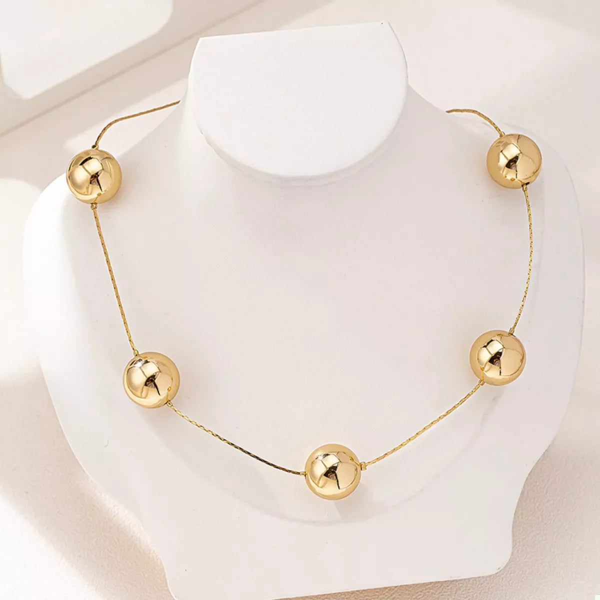 Golden sphere statement necklace by Plush Fashion Hub featuring large, shiny gold spheres on a stylish necklace chain.