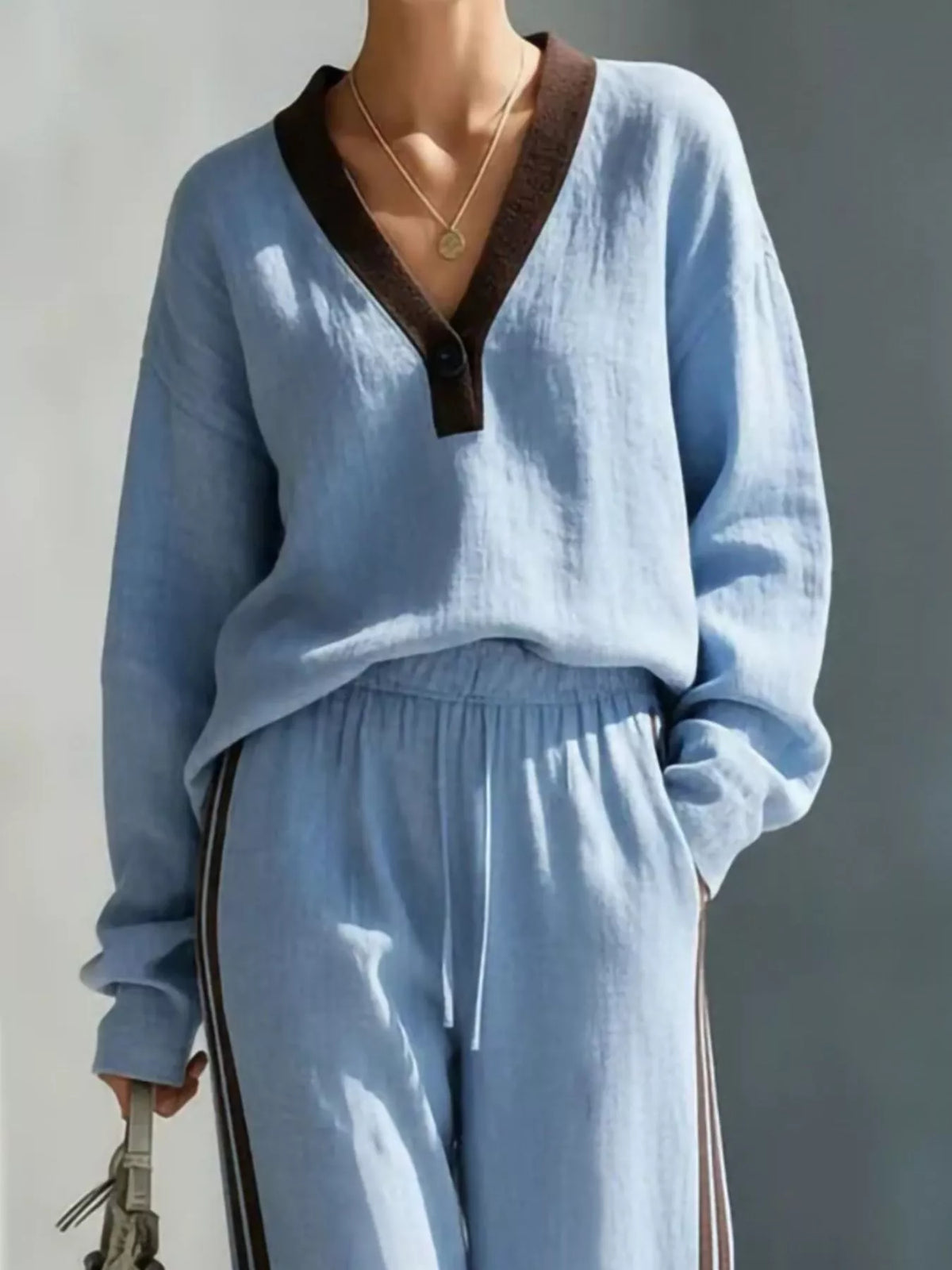 Women's contrast V-neck top and striped pants set by Trendsi, featuring a stylish V-neck blouse and matching striped pants.