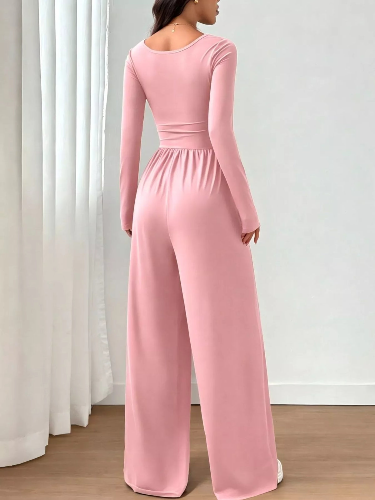 Trendsi ruched square neck wide-leg jumpsuit displayed on a hanger, featuring a fitted bodice and flowing pant legs in a neutral color